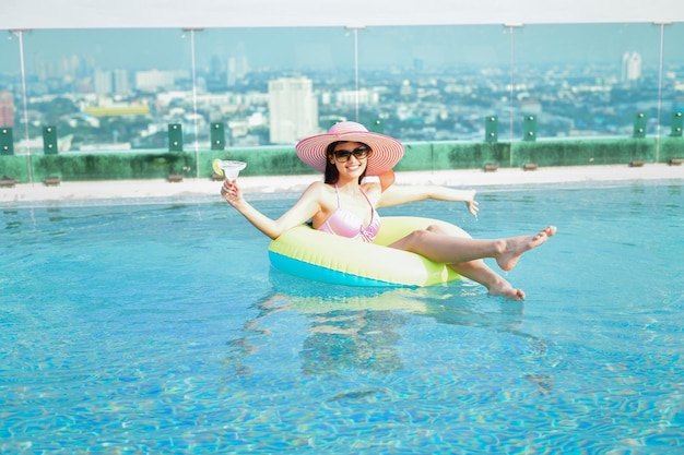 Comprimento completo de mulher sorridente com bebida na piscina