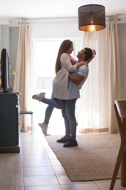 Foto comprimento completo de um jovem casal despreocupado dançando em casa juntos