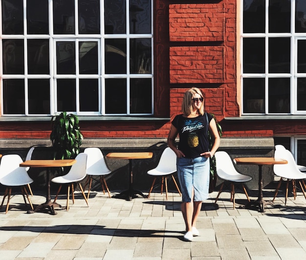 Foto comprimento completo de uma jovem de pé em um café de calçada