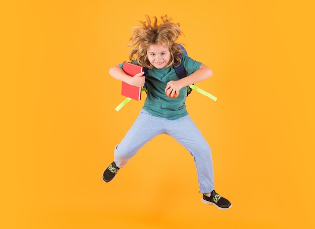 Comprimento total de criança animada pulando Menino de escola em uniforme escolar com mochila pulando em amarelo