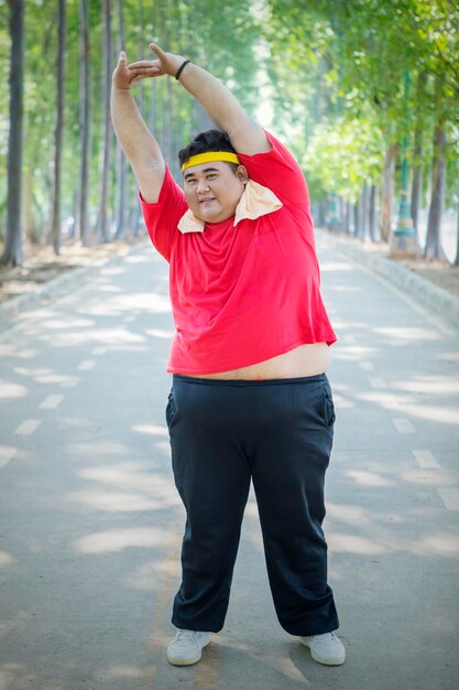 Foto comprimento total de homem de tamanho excessivo se estendendo enquanto está de pé na estrada