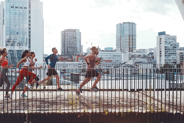 Comprimento total de jovens em roupas esportivas correndo enquanto se exercitam na ponte ao ar livre