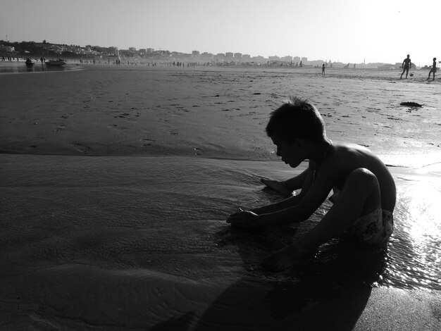 Foto comprimento total de menino na praia contra céu limpo