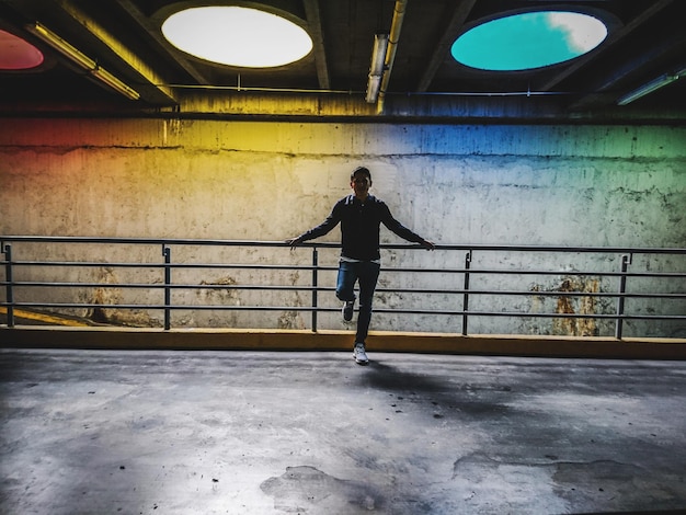 Foto comprimento total de um homem adulto de pé em um corredor iluminado