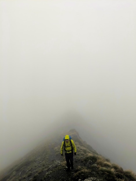 Comprimento total de um homem de pé na montanha durante o tempo neblinho
