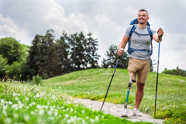 Comprimento total de um jovem simpático e positivo com prótese caminhando ao ar livre e curtindo seu hobby