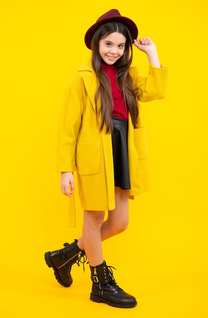 Comprimento total de uma adolescente muito alegre se divertindo de bom humor e posando em roupas casuais isoladas sobre fundo amarelo Roupas de outono