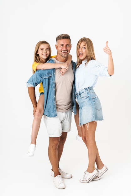 Comprimento total de uma alegre mulher de família caucasiana e um homem com uma menina sorrindo e mostrando o polegar isolado no branco