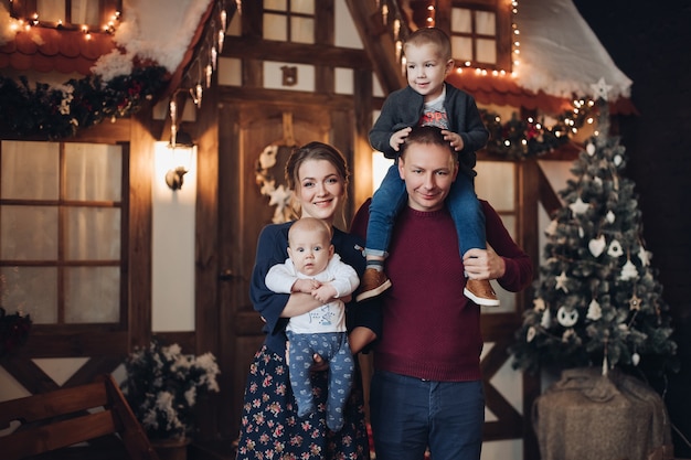 Comprimento total de uma jovem e atraente família caucasiana com dois filhos em um quarto decorado com neve artificial