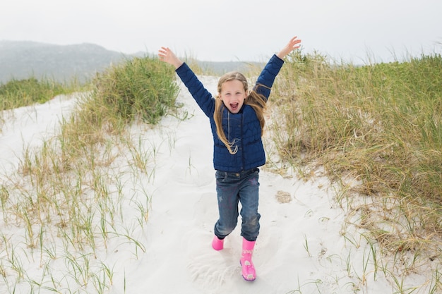 Comprimento total de uma menina alegre correndo na praia