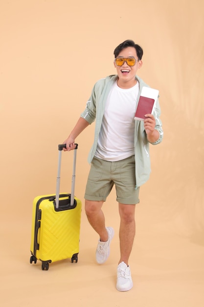 Comprimento total do corpo de um jovem bonito, feliz e alegre homem adulto asiático, com bagagem amarela.