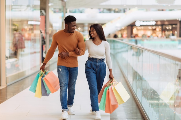 Comprimento total do corpo do casal negro andando com sacolas de compras