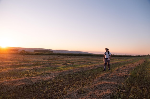 Comprimento total do homem em pé no campo contra o céu durante o pôr do sol
