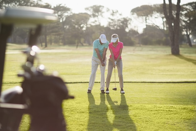 Comprimento total do homem ensinando mulher a jogar golfe
