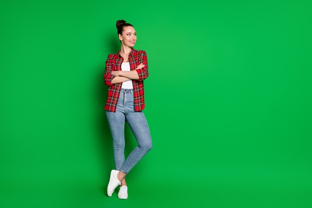 Comprimento total do tamanho do corpo dela ela é legal atraente muito adorável conteúdo alegre alegre garota de cabelos castanhos vestindo uma camisa xadrez posando isolada em um fundo de cor verde vibrante de brilho vívido brilhante