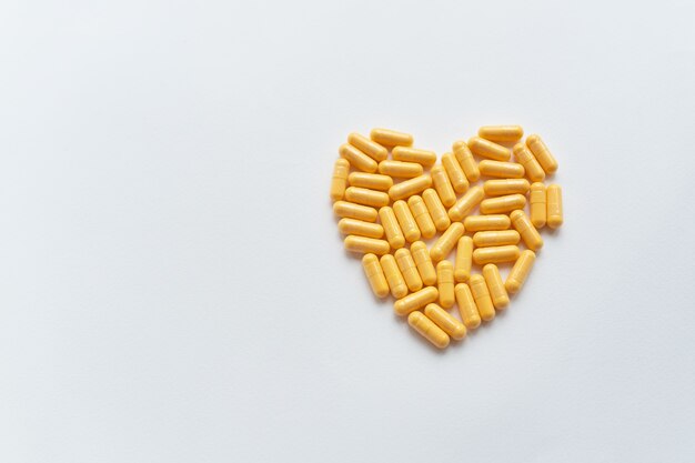 Comprimidos amarelos em forma de coração, saúde e problemas cardíacos. Conceito de medicina e saúde. Lugar para inscrição.