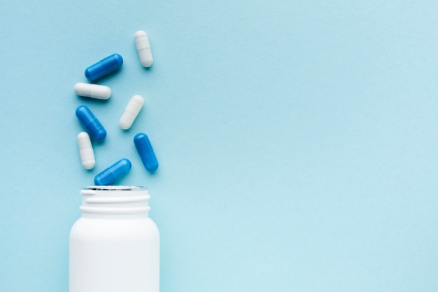 Foto comprimidos azuis e brancos minimalistas com garrafa de plástico