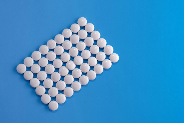 Comprimidos brancos dispostos em um retângulo em um fundo azul