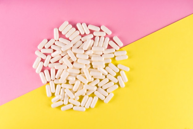 Comprimidos brancos isolados em um fundo de cor pastel. Plano de fundo leigo de comprimidos de medicação e prescrição.