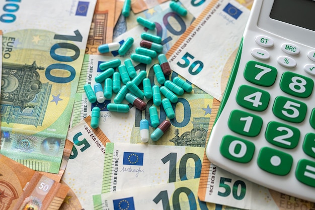 Comprimidos com calculadora na pilha de dinheiro do Euro como conceito de fundo de alto custo de farmácia