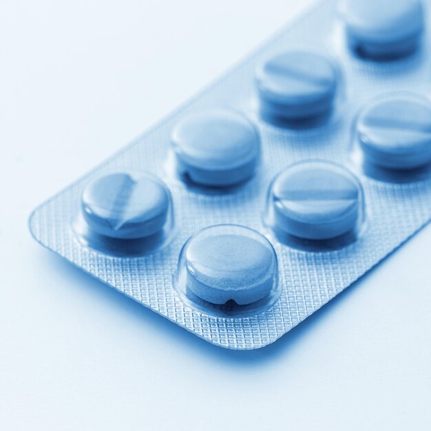 Comprimidos comprimidos que empacotam remédios de farmácia médicos sobre fundo branco azul