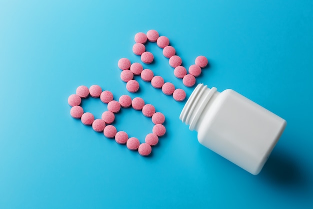 Comprimidos cor-de-rosa na forma da letra B12 em um fundo azul