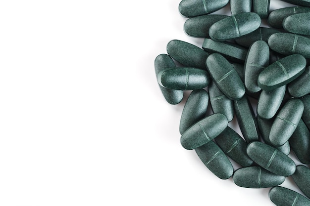 Comprimidos de espirulina verde com multivitaminas em um fundo branco. espaço livre