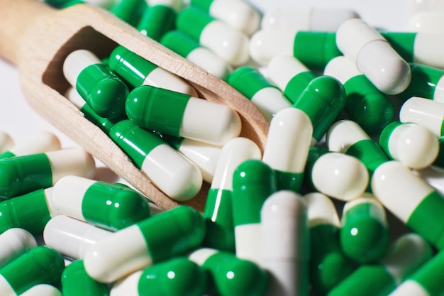 Comprimidos de medicina verde sobre fundo branco em uma colher de pau. farmacêutico classificado