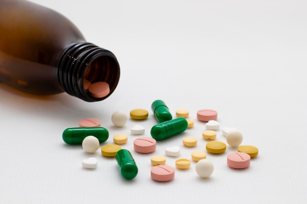 Comprimidos de remédios farmacêuticos e cápsulas e garrafa em fundo branco