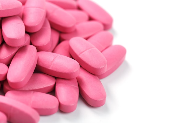 Comprimidos de vitamina rosa para mulheres em um fundo branco.