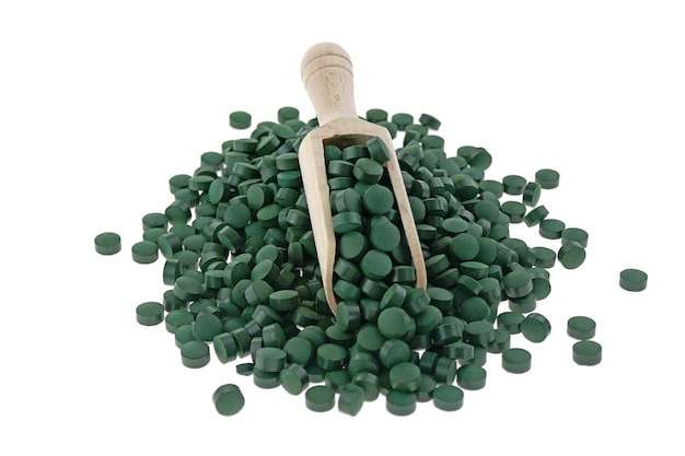 Foto comprimidos do spirulina das algas em uma colher isolada. conceito de comida super. suplementos alimentares para um estilo de vida saudável