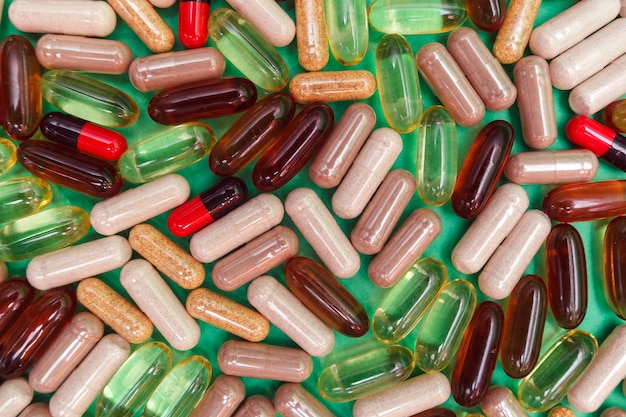 Comprimidos e cápsulas multicoloridos em um fundo verde