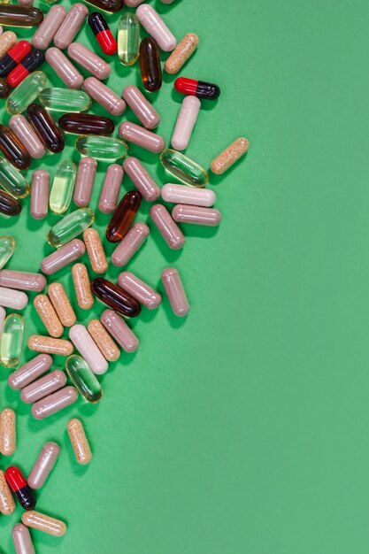Comprimidos e cápsulas multicoloridos em um fundo verde