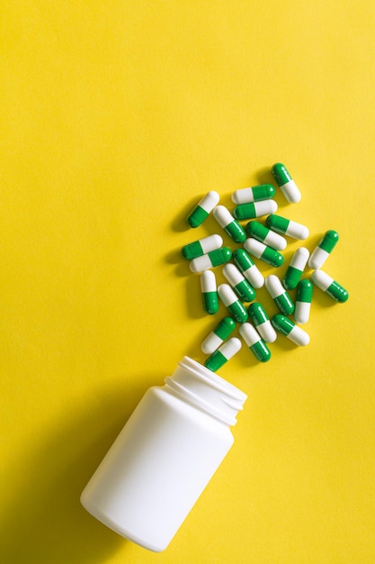 Comprimidos e frascos de comprimidos em fundo amarelo, frasco de vidro médico marrom e alguns comprimidos ao redor
