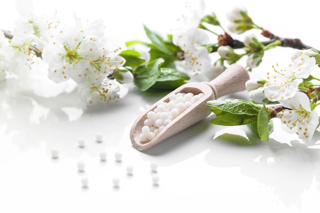 Comprimidos homeopáticos com flores da primavera em fundo branco