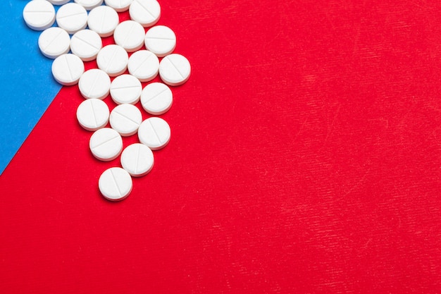 Comprimidos médicos brancos sobre um fundo vermelho e azul de duas cores