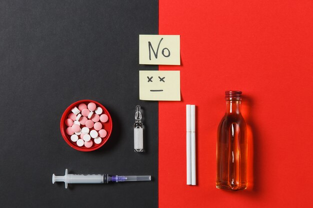 Comprimidos redondos coloridos de medicação, pílulas, agulha de seringa vazia, garrafa de cigarros com ampola de álcool