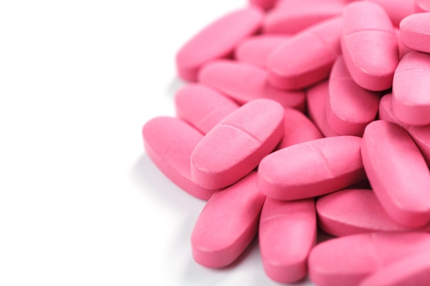 Comprimidos rosa com multivitaminas em um fundo branco. Espaço livre