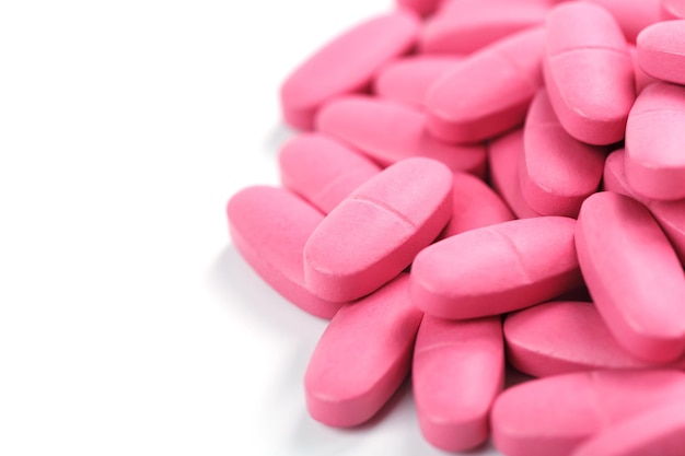 Comprimidos rosa com multivitaminas em um fundo branco. espaço livre