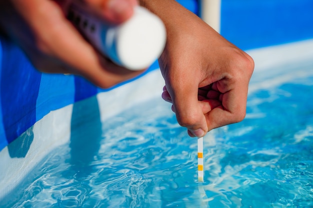 Comprobación de la calidad del agua de una piscina con la ayuda de una tira reactiva con valor de ph cloro y algicida