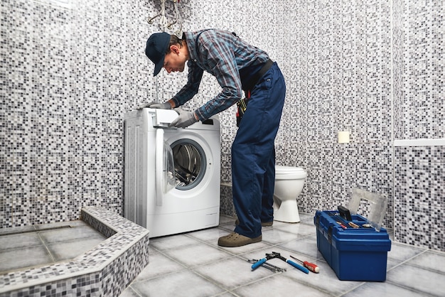 Comprobación de la lavadora trabajo fontanero hombre de trabajo en el baño.