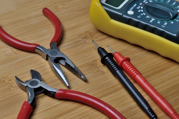 Comprobador eléctrico y kit de herramientas de electrónica en mesa de madera.