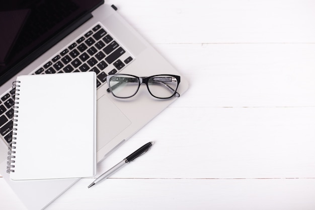 Computador, caderno em branco, caneta e óculos. Escritório em casa e conceito de carreira.