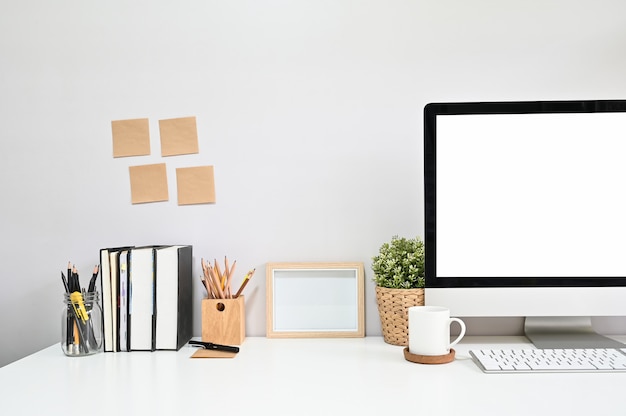 Computador colhido do tiro no espaço de trabalho com café, livro, lápis e nota pegajosa.