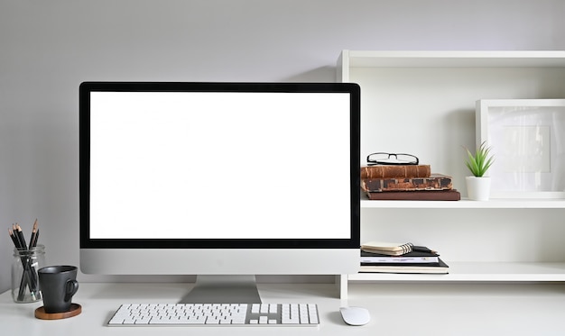 Computador de maquete do espaço de trabalho na mesa de escritório e livros, moldura e livros nas prateleiras.