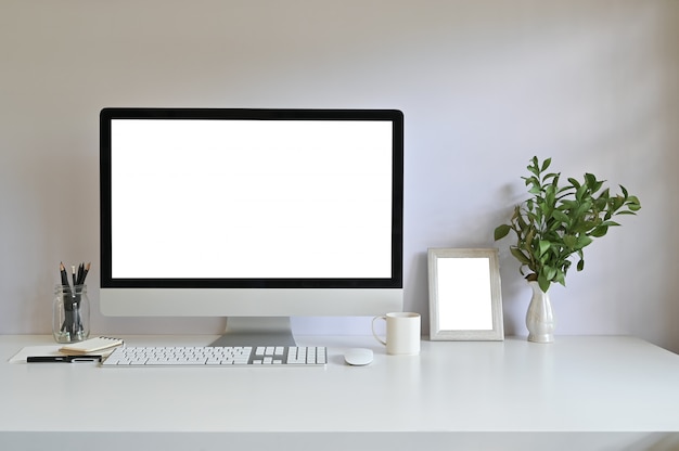 Computador do espaço de trabalho e frame da foto, café com a decoração da planta na mesa de escritório.