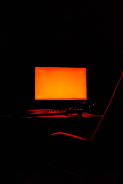 Foto computador iluminado em mesa na sala escura