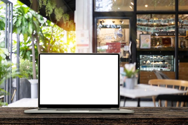 Computador laptop com tela em branco sobre mesa de madeira com restaurante blur café com luz bokeh abstrata desfocada