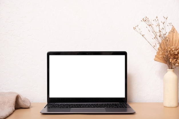 Computador portátil com buquê de grama seca de tela em branco e suéter Modelo de design de interiores com estilo boho influenciador estético com espaço de cópia de laptop de maquete
