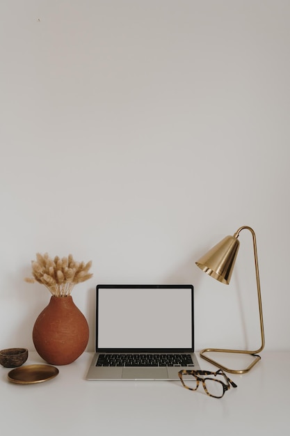 Computador portátil com maquete de tela de espaço de cópia em branco Minimalista senhora chefe escritório em casa mesa de trabalho com óculos flores Estética boêmia loja online loja blog modelo de marca de mídia social